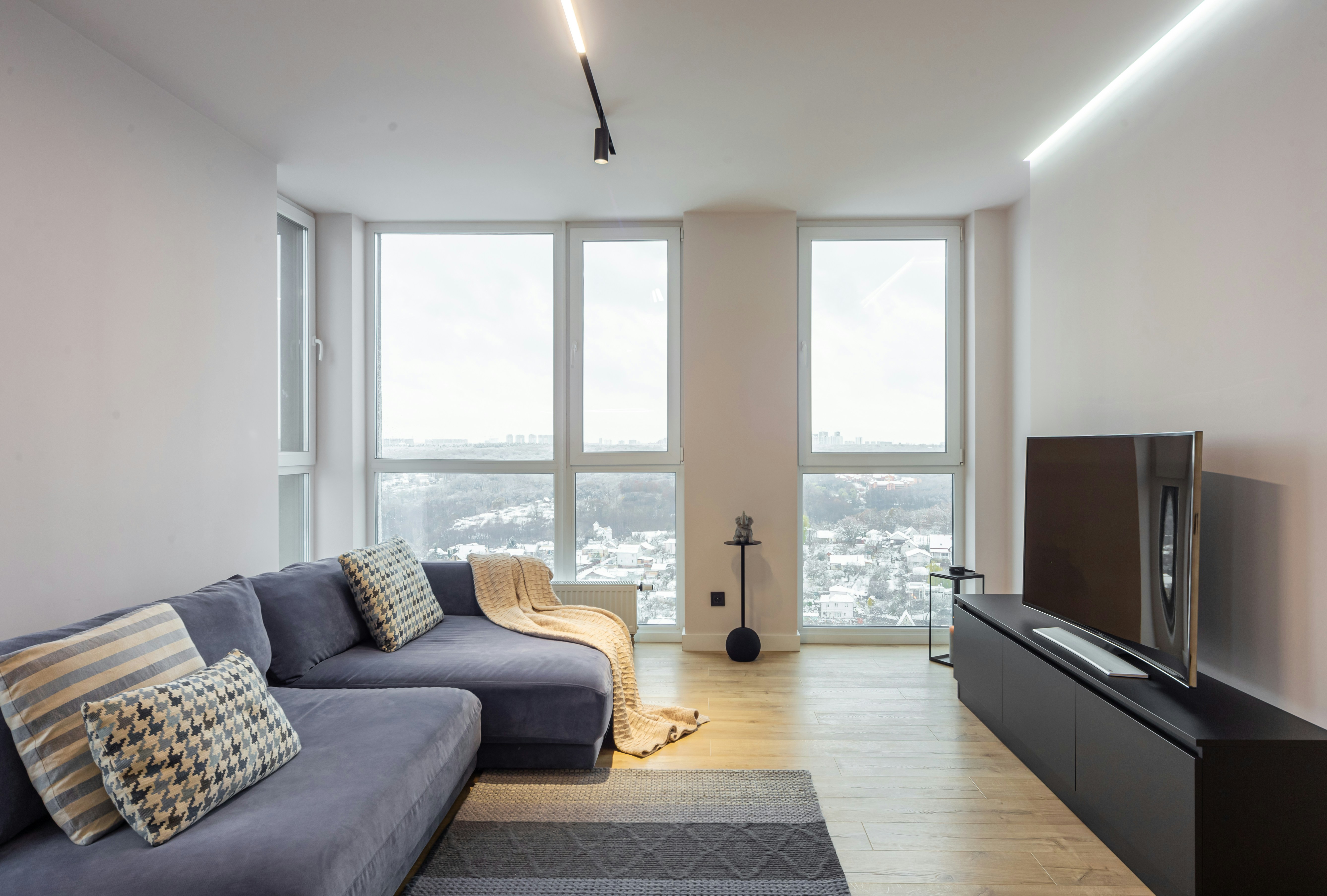 A living room with a couch a television and a large window